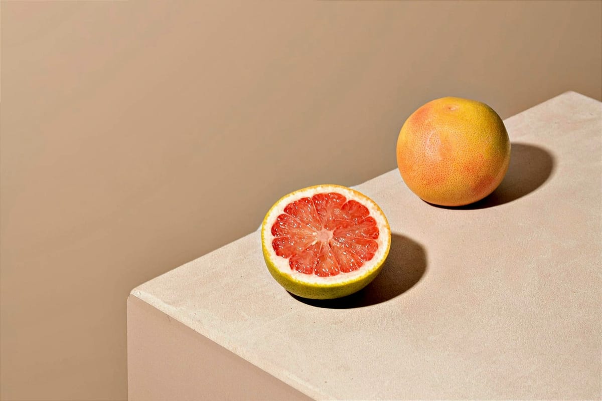 half of a grapefruit and a whole grapefruit on a table