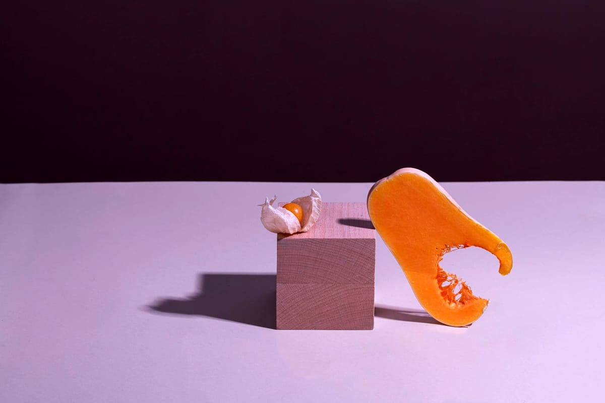 A ripe papaya, bitten and leaning against a wooden block on a purplish background