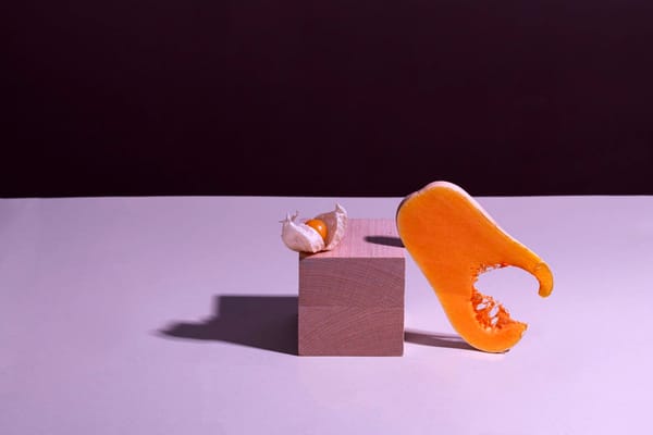 A ripe papaya, bitten and leaning against a wooden block on a purplish background