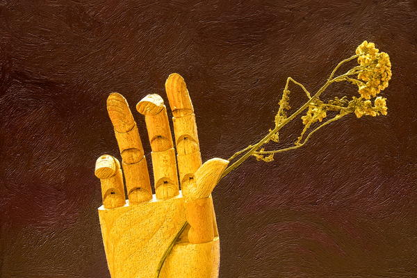 A carved wooden hand grasping a delicate flower.