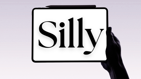 A silhouetted hand holds a tablet displaying the word ‘Silly’ in bold serif type—featured image for an article exploring the etymology of the word.